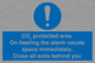 MN7906: CO₂ protected area. On hearing the alarm vacate space immediately. Close all exits behind you